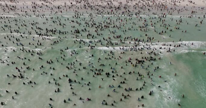 Aerial close-up panning view of crowded overtourism Muizenberg beach, Cape Town South Africa 