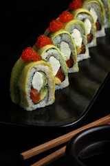 A beautifully presented plate of sushi rolls topped with bright orange fish roe. 