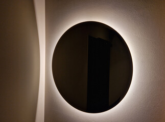circular mirror with a lamp around the perimeter. then a simple mirror on gray concrete plaster...