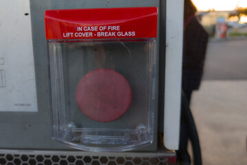 in case of fire emergency lift cover or break glass text sign on red button mounted on station gas