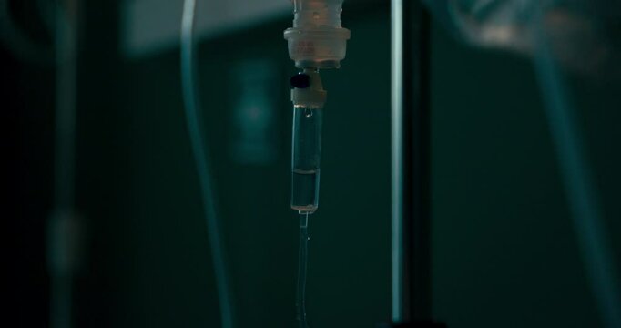 IV drip in the foreground with a hospital room in the background.