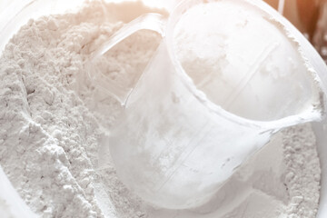 Transparent measuring cup in white flour for baking preparation.