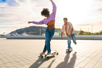 Young multiethnic modern couple with skateboards dating outdoors - Two friends having fun skating...