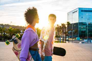 Young multiethnic modern couple with skateboards dating outdoors - Two friends having fun skating...