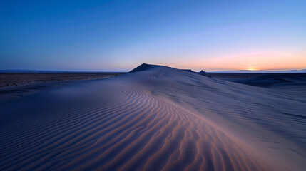 A tranquil capture of the sandstone formations in Monument Valley at dusk, with smooth ripples in the sand and faint pastel light on the horizon