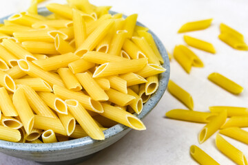 close up of raw penne pasta in a bowl