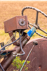 A rusty old tractor with a blue steering wheel