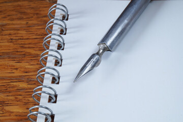 A fountain pen with a pen and a notebook on a wooden table