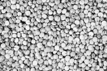 Close-up view of a large amount of white tablets against a neutral blurred backdrop.