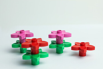 Obraz premium Colorful plastic toy flowers on a white background, shallow depth of field