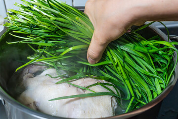 putting fresh chives on the boiling chicken