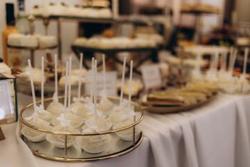 A table full of desserts and drinks with a white tablecloth. The desserts are arranged in a way that makes them look like they are on display. Scene is celebratory and inviting