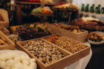 A beautifully arranged charcuterie board featuring an assortment of cheeses, cured meats, crackers, nuts, fruits, and spreads, displayed on a wooden table with serving utensils and dishes.
