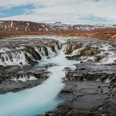 Bruarafoss waterfall with stunning turquoise waters under a bright sky in south Iceland