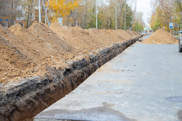 earthen trench under the asphalt street surface for large diameter water pipe. Repair, renovation or replacement of municipal equipment in city