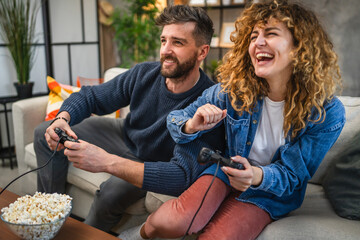 excited young adult couple playing video game sitting on sofa at home © Miljan Živković