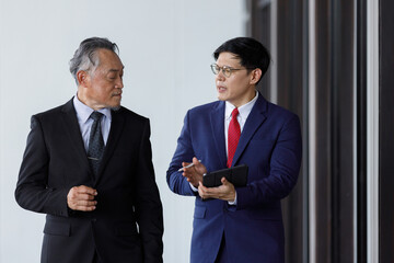 Senior executives with young businessmen talking information strategic plans and reviewing company quarterly performance. Working together between two generations.