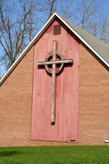 Generated image - the side of a brick building with a large wooden cross mounted on a red wooden panel
