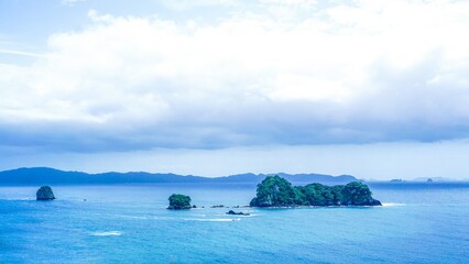 Scenic coastline of New Zealand showcasing lush islands surrounded by clear blue waters on a tranquil day