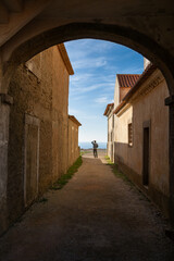 Obraz premium Silhouette of a Man Standing in an Archway Overlooking the Ocean at Santuário de Nossa Senhora do Cabo Espichel, Portugal. December 2024