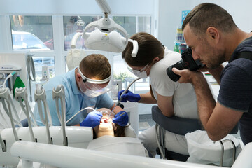 Dental treatment. Woman on dental examination. Professional equipment in dental clinic. photographer takes pictures of dental treatment process videographer shoots video man