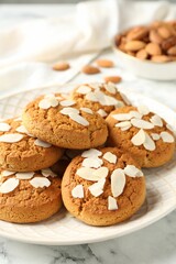 Tasty cookies with almond flakes and nuts on white marble table, closeup