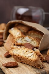 Paper bag with tasty almond biscuits (Cantuccini) and nuts on wooden board, closeup