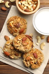 Tasty cookies with nuts and milk on wooden table, flat lay