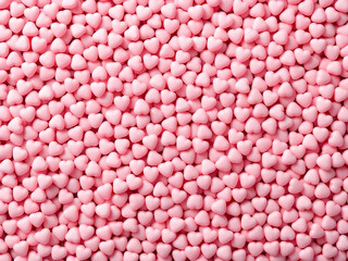 Pink heart-shaped candies in abundance, glossy texture.