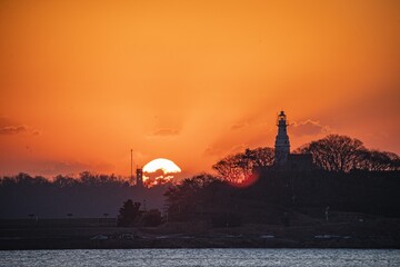 Silhouette of Little Green Island Lighthouse at sunrise with vibrant colors reflecting on the water