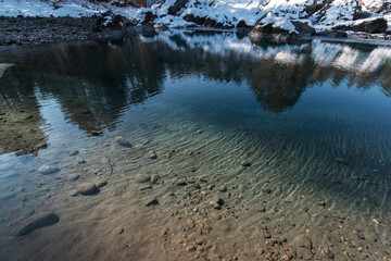 Unfrozen lake with snowy mountains reflecting on its icy surface, Altai Mountains