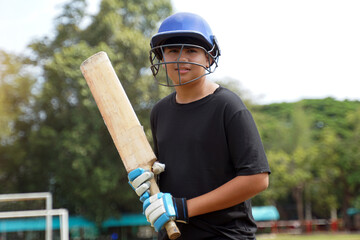 A cricketer holds the bat while waiting for the cricket ball. while practicing on the field. Soft...