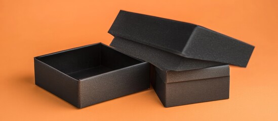 Elegant black gift boxes stacked at an angle on a vibrant orange background, featuring ample copyspace for personalized text or branding.