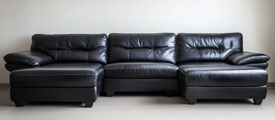 Black leather sectional sofa on laminate floor against plain white wall, copyspace available
