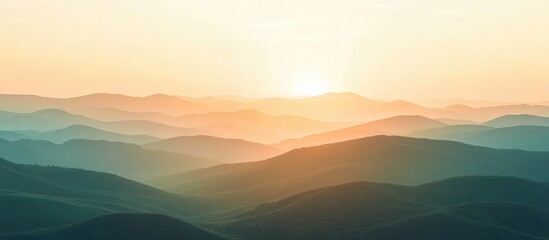 Fototapeta premium Golden sunset over rolling green hills and valleys with soft blue hues, expansive landscape ideal for text placement and visual depth.