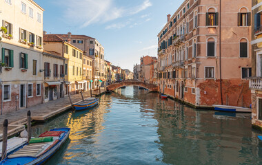 Tranquil Venetian Canal with Boats and Stone Bridge