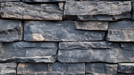 Textured black stone wall background with irregular shaped stones arranged in layers ideal for construction or design projects with Copy Space.