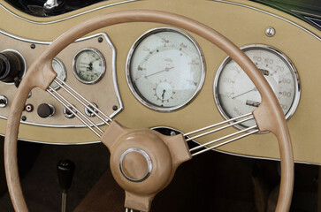 Dashboard layout of an old 1940s sportscar. Instrumentation and steering wheel.