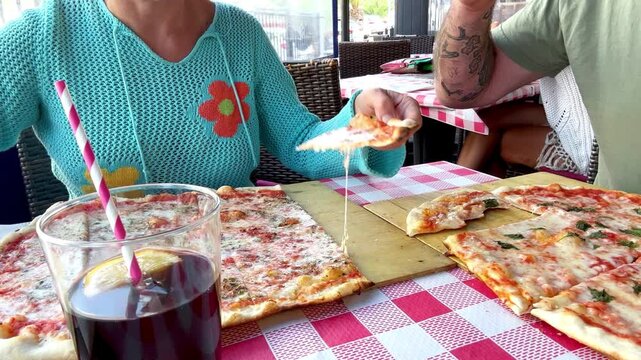 Man and woman on a romantic lunch date at a pizzeria dehor, sharing a freshly baked Italian pizza, dressed in casual spring attire, surrounded by Mediterranean flavors and a relaxed setting.