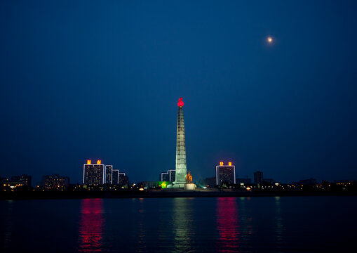 Juche tower with red flame in front of the Taedong river at night, Pyongan Province, Pyongyang, North Korea