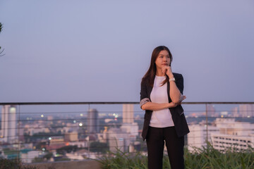 Businesswoman standing on a rooftop at sunset, contemplating future projects while admiring the vibrant cityscape, filled with ambition and aspirations for success and growth