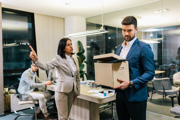 Businessman got fired from his job. Taking box with his personal stuff from the office.