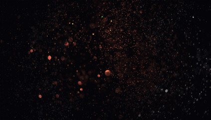 Holiday abstract bokeh on black background. Festive sparkling gold dust. Holiday concept