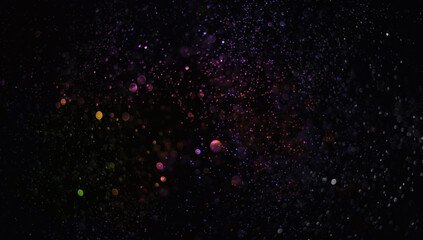 Holiday abstract bokeh on black background. Festive sparkling gold dust. Holiday concept