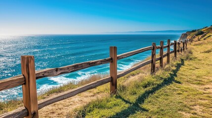 Obraz premium The weathered wooden fence winds along the coastline, framing breathtaking ocean views, with sunlight dancing on the waves in the distance.