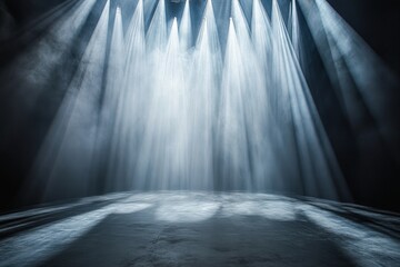 Intense rays of light converge on a blank stage creating a dramatic atmosphere with soft, diffused edges merging into darkness