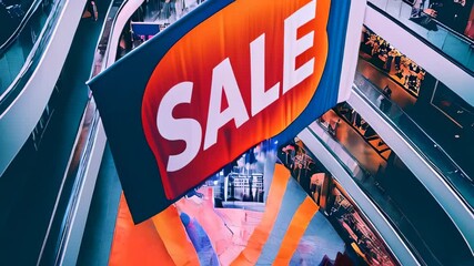 Large banner promoting sale hangs over busy shopping center during afternoon