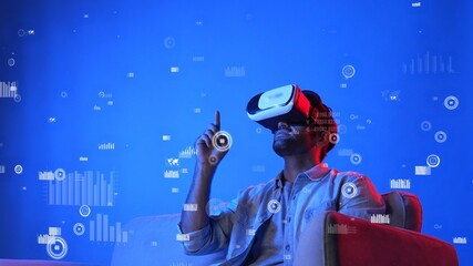Business man wearing VR headset while looking at financial graph and analyzing statistic chart. Attractive investor sitting at sofa and turning VR headset on and checking graph. Technology. Apparatus.