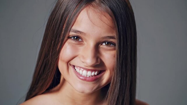 Young girl with beautiful smile on grey background. Teeth whitening