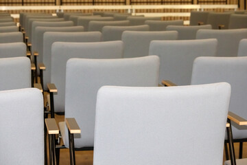 
Fragment of an empty conference hall or auditorium with rows of gray chairs.